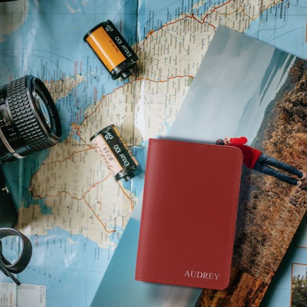 red passport on a world map with a camera and film