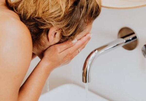 woman washing face after putting on the best korean face mask