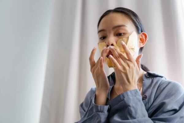 woman putting on best korean face mask