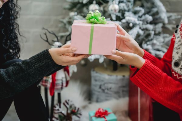 girl passing another girl a pink present