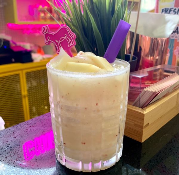 glass of pina colada with a purple straw 