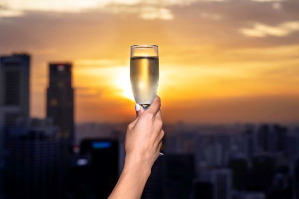 person holding champagne glass against sun set