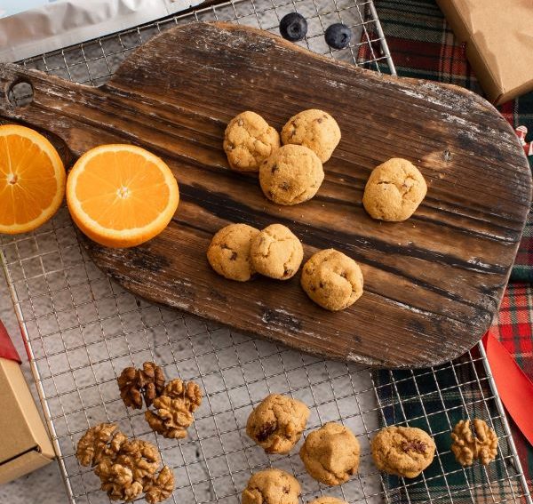 orange cookies on wooden board next to fresh oranges 