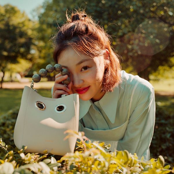 korean model holding koimooi mini nana bag with top handle in a garden
