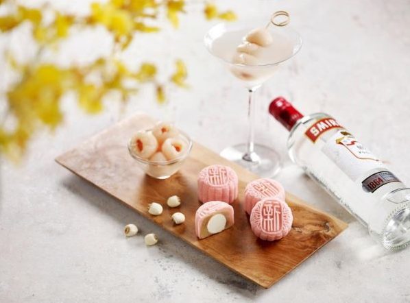 pink lychee martini snowskin mooncakes on a wooden board with a bottle of vodka and glass of martini best snowskin mooncakes singapore 2022