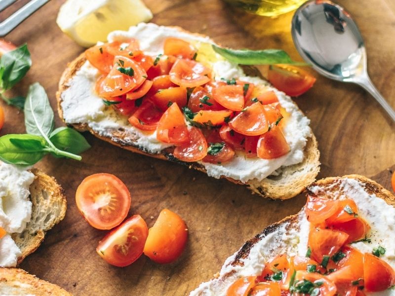ricotta toast with cherry tomatoes and herbs on wooden board