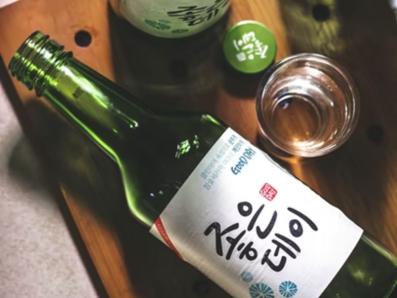bottle of soju and soju cup on a wooden table