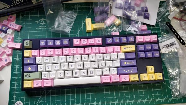 custom keyboard singapore with pink, purple, white and yellow keycaps on a green mat