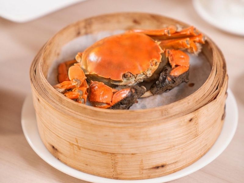 Cooked hairy crab in a bamboo steamer on a plate