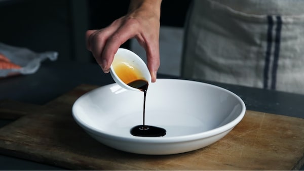 person pouring black sauce on plate