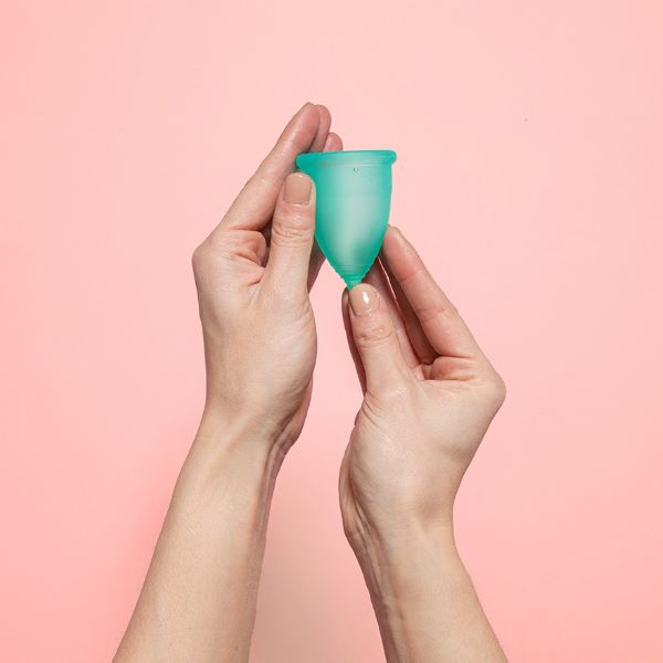 person holding green menstrual cup on pink background best menstrual cups singapore