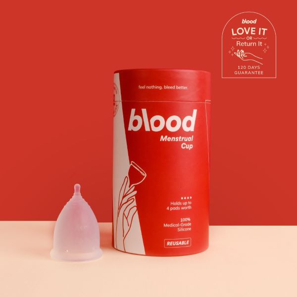 clear menstrual cup next to blood menstrual cup box on red background