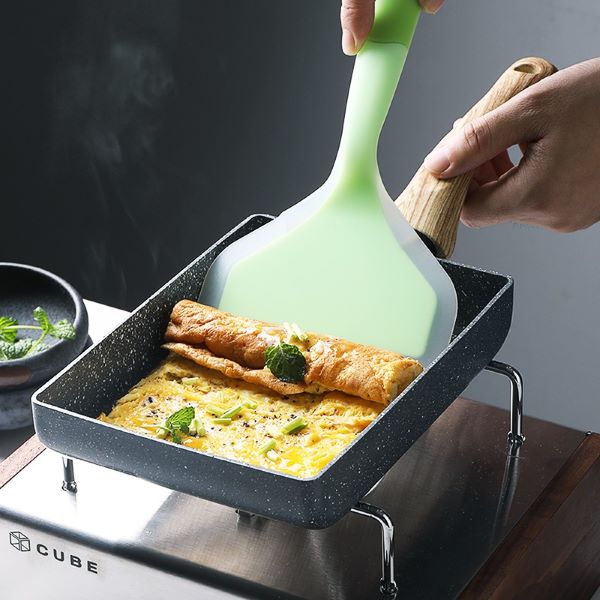 person rolling up an egg roll in a square pan