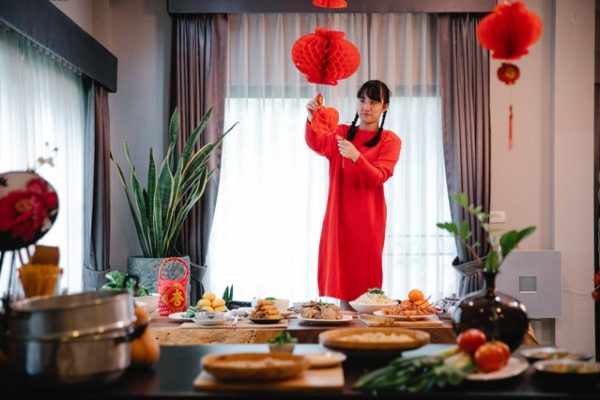 spring cleaning cny girl in red putting up lanterns