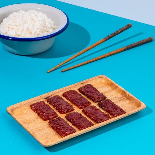 sliced bak kwa on wooden plate on a blue table