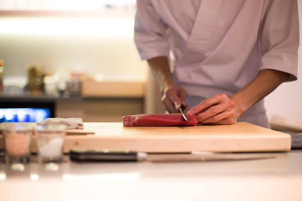 japanese chef slicing tuna sashimi on wooden board