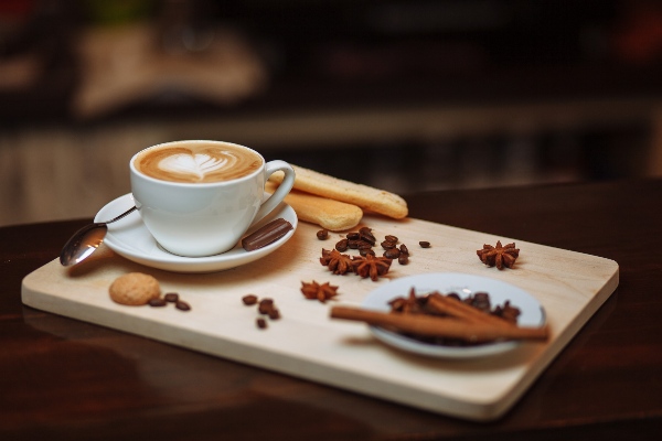 cappuccino with lady fingers, cinnamon stick and star anise on tray