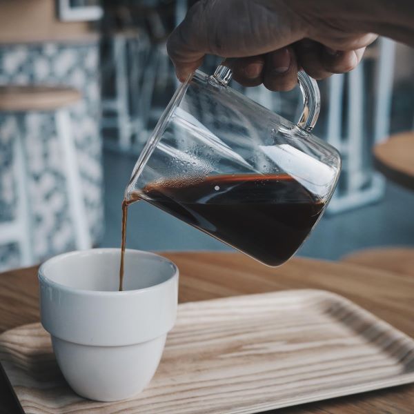 person pouring black coffee into a white cup coffee workshops singapore