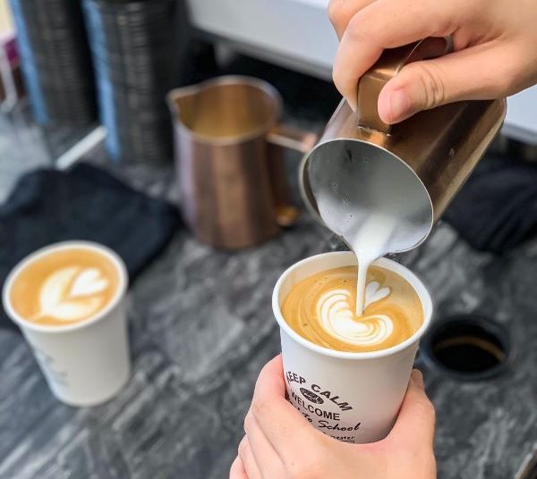 person doing a heart shape latte art in a paper cup coffee workshops singapore