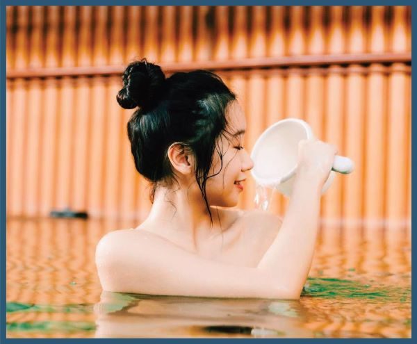 lady in bun dousing water on her shoulders in an onsen in singapore