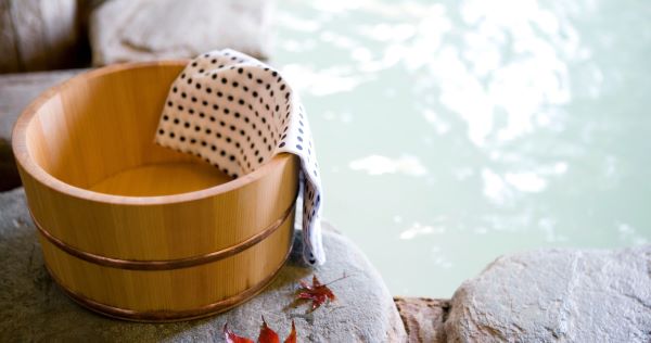 onsen wooden pail with towel inside next to an onsen bath