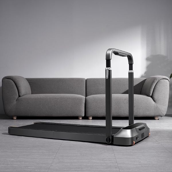 foldable treadmill in living room in front of a grey sofa