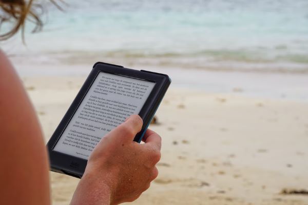 person reading kindle at the beach