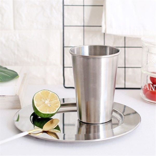 stainless steel tumbler on a metal plate with a lime beside it