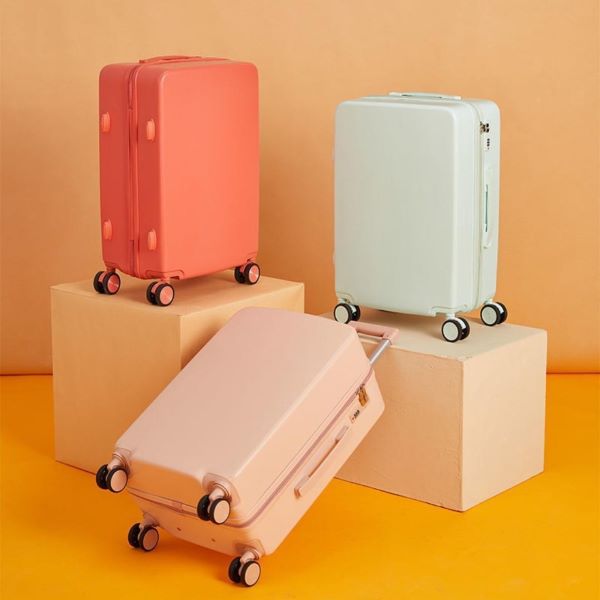 baby pink, coral pink, and baby blue hard case luggage against yellow background
