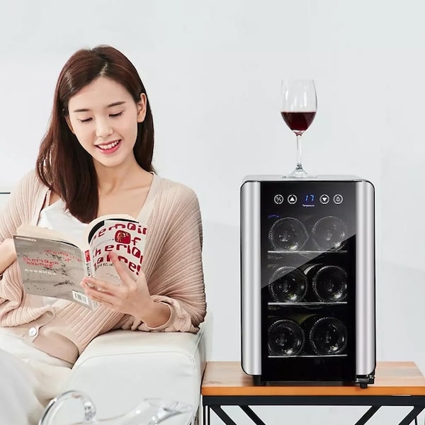 lady sitting on a sofa next to a small wine chiller with a glass of red wine on top 