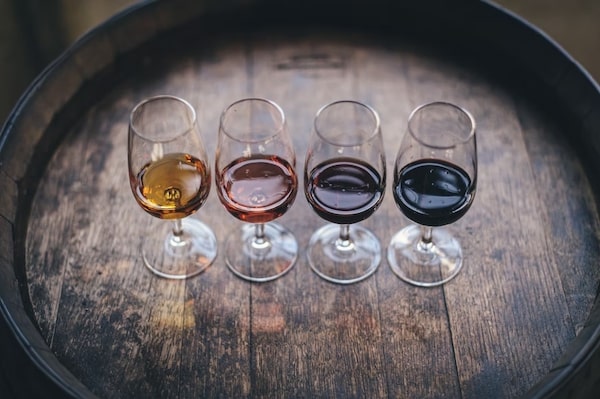 glasses of different types of wine on a wooden barrel