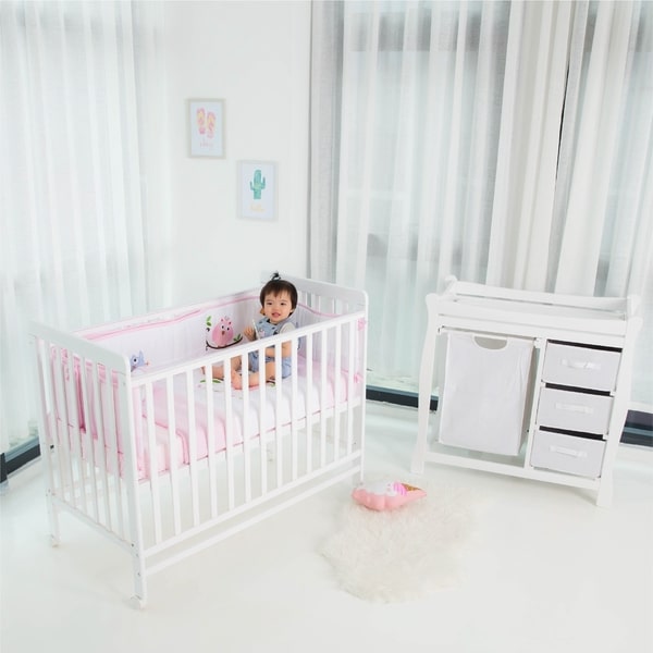 baby sitting in a white baby cot