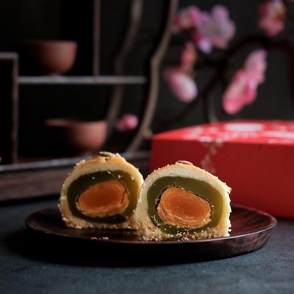 shanghai mooncake with green tea paste and egg yolk center cut in half on a plate