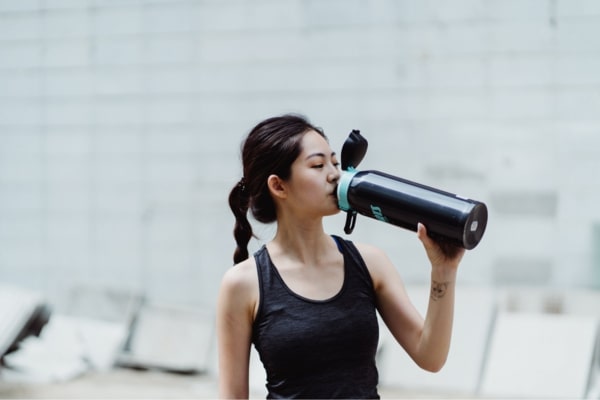 woman in activewear drinking from a water bottle