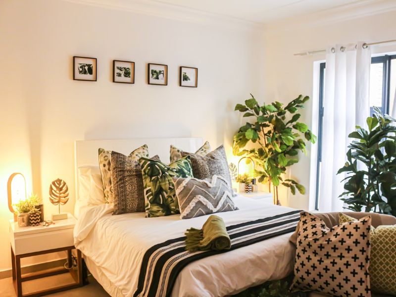 bedroom with photo frames on wall, throws, and green plants