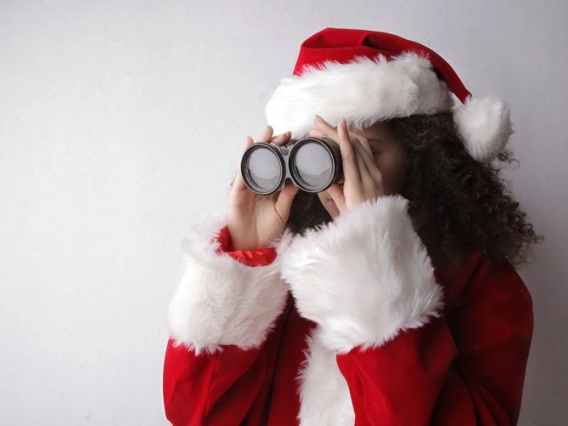 girl in santa claus costume holding binoculaurs