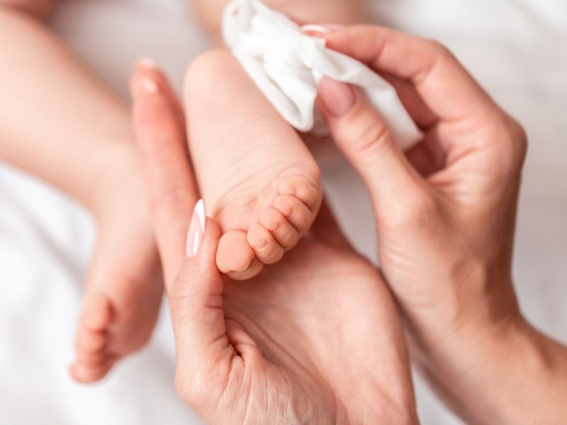 mum wiping baby's feet with baby wipes