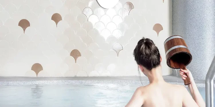 lady in bun dousing water with wooden pail at yunomori silk onsen in singapore