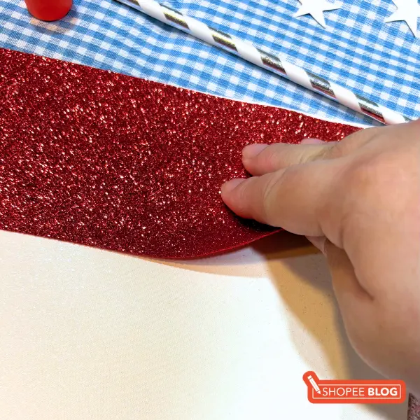 singapore flag craft - pasting red glitter paper on white cardstock