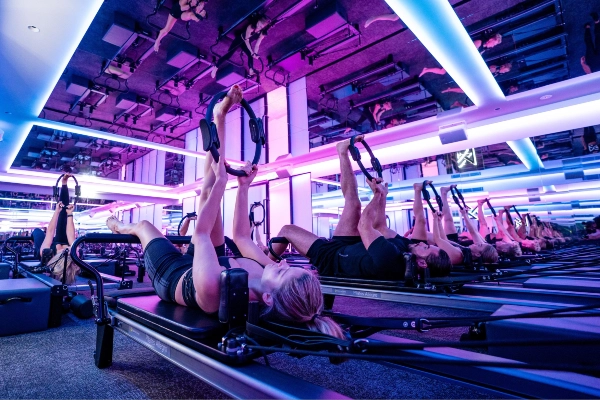 group of ladies using the pilates ring in a neon-lit studio, VAURA fitness, one of the best pilates studio in singapore