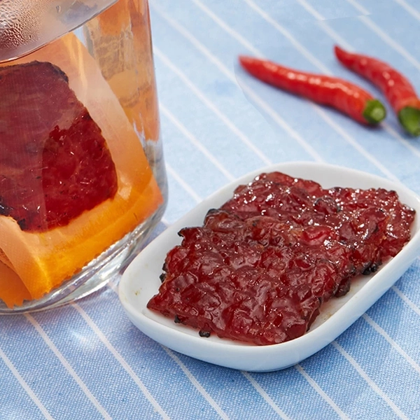 Bee Cheng Hiang mini bak kwa on a saucer plate, with chilli padi in the background