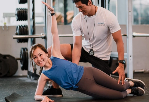 Gold’s Gym best personal trainers guiding client on a good cooldown stretch