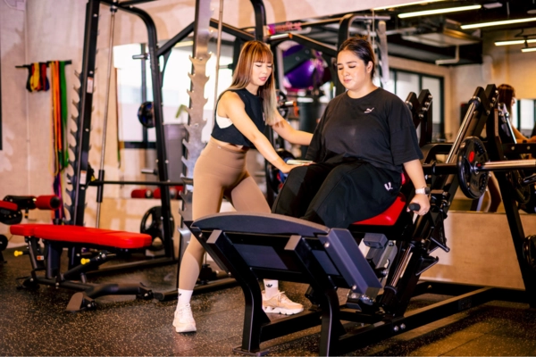 MSFIT best personal trainers guiding woman on a squat machine