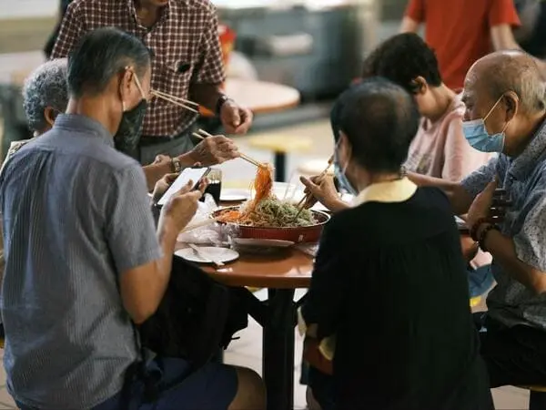 group of elders sitting at the hawker centre doing lo hei