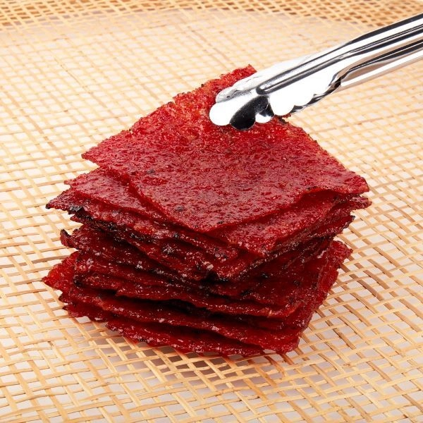 using metal tongs to pick up some of the best bak kwa in Singapore by Wu Chin Leong